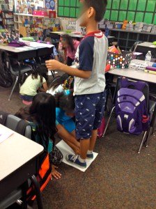 Tracing each other's feet and hands to create their self-portrait.